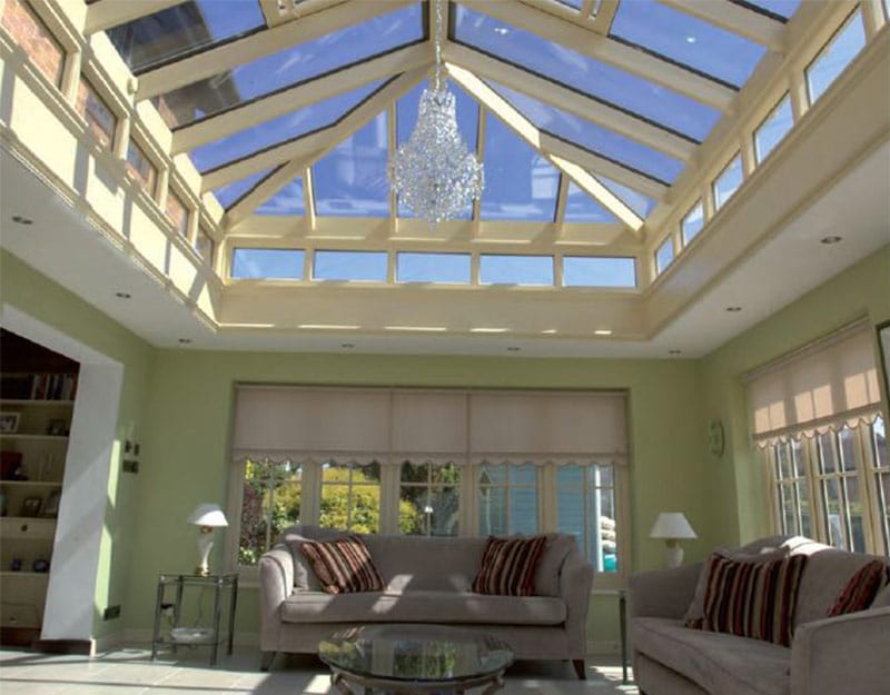 Photograph of a glass conservatory roof with a chandelier hanging from the centre. The room is bright with lots of windows.